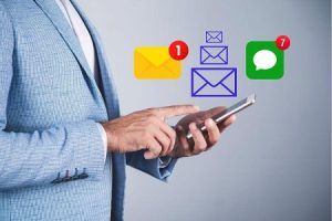 Businessman holding a smartphone with SMS and WhatsApp message notifications floating above the screen.
